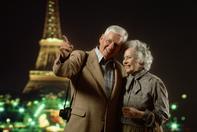 An older couple posing for a picture in front of the eiffel tower.